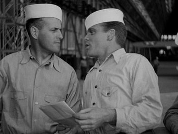 Movie still from “Here Comes the Navy” (1934), directed by Lloyd Bacon – Two men wearing hats are talking to each other; Medium shot, Over the shoulder angle
