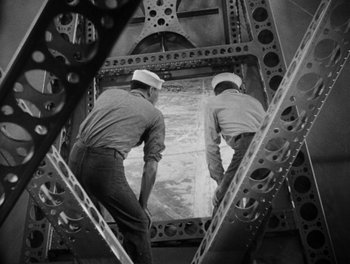 Movie still from “Here Comes the Navy” (1934), directed by Lloyd Bacon – A couple of men standing next to each other on a bridge; Medium shot, Low angle