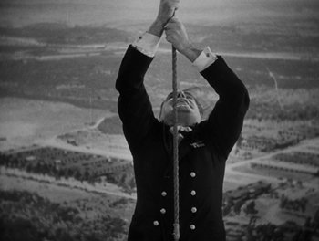 Movie still from “Here Comes the Navy” (1934), directed by Lloyd Bacon – A man in a military uniform holding a rope; Medium shot, Low angle