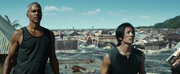 Movie still from “Hereafter” (2010), directed by Clint Eastwood – A man standing next to another man on a beach; Medium shot, Low angle