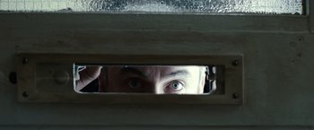 Movie still from “Hereafter” (2010), directed by Clint Eastwood – A man looking through a window at something in the house; Extreme Close Up shot, Low angle