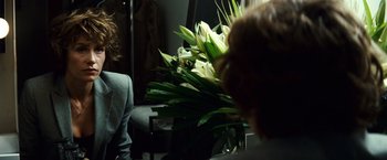 Movie still from “Hereafter” (2010), directed by Clint Eastwood – A woman sitting in front of a large bouquet of white flowers; Medium shot, Over the shoulder angle