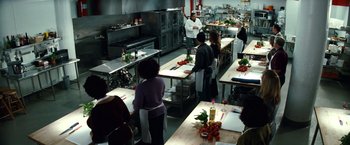 Movie still from “Hereafter” (2010), directed by Clint Eastwood – A group of people in a kitchen preparing food; Wide shot, High angle