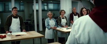 Movie still from “Hereafter” (2010), directed by Clint Eastwood – A group of people standing around a table; Medium shot, Over the shoulder angle