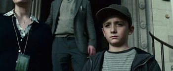Movie still from “Hereafter” (2010), directed by Clint Eastwood – A young boy with a hat on and a man in a suit behind him; Close Up shot, Low angle