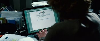 Movie still from “Hereafter” (2010), directed by Clint Eastwood – A person sitting in front of a laptop computer on top of a desk; Close Up shot, High angle