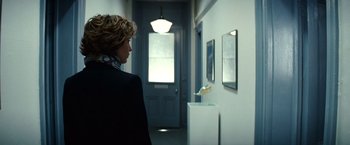 Movie still from “Hereafter” (2010), directed by Clint Eastwood – A woman standing in front of a door looking in a mirror; Medium shot, Low angle