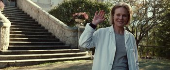 Movie still from “Hereafter” (2010), directed by Clint Eastwood – A woman in a white coat waving at the camera; Medium shot, Low angle
