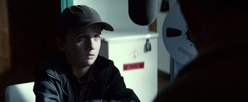Movie still from “Hereafter” (2010), directed by Clint Eastwood – A young boy wearing a baseball cap in front of a refrigerator; Close Up shot, Over the shoulder angle