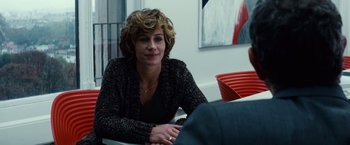 Movie still from “Hereafter” (2010), directed by Clint Eastwood – A woman sitting at a table in front of a painting; Close Up shot, Over the shoulder angle