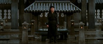 Movie still from “Hero” (2002), directed by Yimou Zhang – A man standing in front of an asian style building; Wide shot, Low angle
