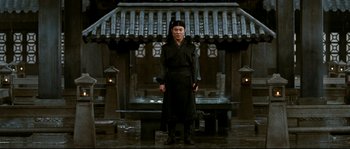 Movie still from “Hero” (2002), directed by Yimou Zhang – A man standing in front of an asian style building; Wide shot, Low angle