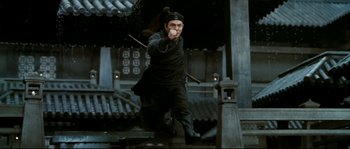 Movie still from “Hero” (2002), directed by Yimou Zhang – A man in a black outfit holding a sword; Wide shot, Low angle
