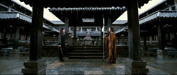 Movie still from “Hero” (2002), directed by Yimou Zhang – Two men and a woman are standing in front of a building; Wide shot, Low angle