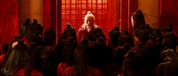 Movie still from “Hero” (2002), directed by Yimou Zhang – An old man with long white beard standing in front of a group of people; Medium shot, Over the shoulder angle