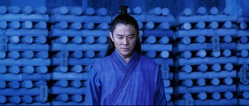 Movie still from “Hero” (2002), directed by Yimou Zhang – A man in a blue robe with a long black wig on top of his head; Medium shot, Low angle