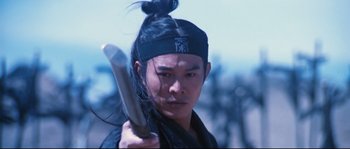 Movie still from “Hero” (2002), directed by Yimou Zhang – A man holding a sword in his hand; Close Up shot, Low angle