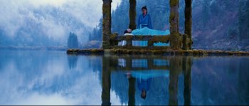 Movie still from “Hero” (2002), directed by Yimou Zhang – A person sitting on a bench near a body of water; Wide shot, High angle