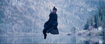 Movie still from “Hero” (2002), directed by Yimou Zhang – A man flying through the air while holding an umbrella; Wide shot, Low angle