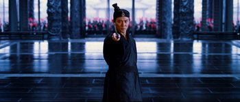 Movie still from “Hero” (2002), directed by Yimou Zhang – A man in a black robe holding something in his hand; Medium shot, Over the shoulder angle