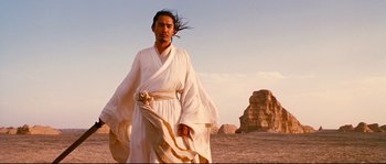 Movie still from “Hero” (2002), directed by Yimou Zhang – A man in a white robe standing in a desert; Medium shot, Low angle