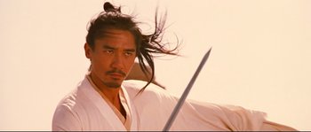 Movie still from “Hero” (2002), directed by Yimou Zhang – A man in a white robe holding a sword in his hand; Close Up shot, Low angle