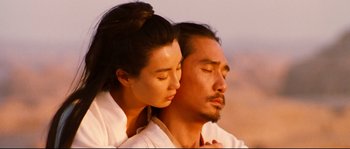 Movie still from “Hero” (2002), directed by Yimou Zhang – A man and a woman embracing each other in the desert; Close Up shot, Low angle