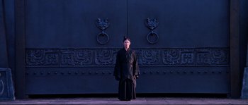 Movie still from “Hero” (2002), directed by Yimou Zhang – A man in a black robe standing in front of a door; Wide shot, Low angle