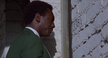 Movie still from “Hickey & Boggs” (1972), directed by Robert Culp – A man in a green jacket leaning against a wall; Close Up shot, Low angle