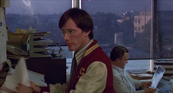 Movie still from “Hickey & Boggs” (1972), directed by Robert Culp – A man in a red and white jacket is at a desk with papers; Medium shot, Low angle