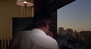 Movie still from “Hickey & Boggs” (1972), directed by Robert Culp – A man looking out of a window at a city skyline; Medium shot, Over the shoulder angle