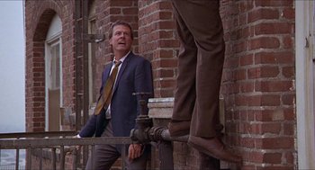 Movie still from “Hickey & Boggs” (1972), directed by Robert Culp – A man in a suit and tie leaning against a brick wall; Medium shot, Low angle