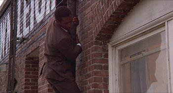 Movie still from “Hickey & Boggs” (1972), directed by Robert Culp – A man in a suit climbing a brick wall; Medium shot, Low angle