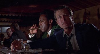 Movie still from “Hickey & Boggs” (1972), directed by Robert Culp – A couple of men sitting at a dinner table; Medium shot, Low angle