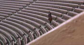 Movie still from “Hickey & Boggs” (1972), directed by Robert Culp – A man walking across a stadium with a bag; Extreme Wide shot, High angle