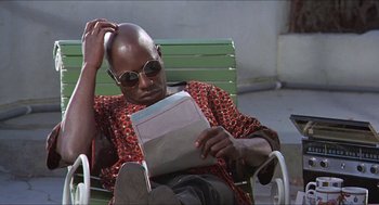 Movie still from “Hickey & Boggs” (1972), directed by Robert Culp – A man sitting in a chair reading a book; Close Up shot, High angle