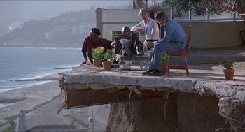 Movie still from “Hickey & Boggs” (1972), directed by Robert Culp – A group of people sitting on top of a wooden structure; Wide shot, High angle