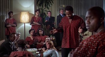 Movie still from “Hickey & Boggs” (1972), directed by Robert Culp – A group of people sitting and standing in a room; Medium shot, Over the shoulder angle