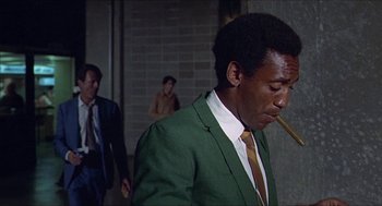 Movie still from “Hickey & Boggs” (1972), directed by Robert Culp – A man in a green suit smoking a cigarette; Medium shot, Low angle