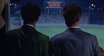 Movie still from “Hickey & Boggs” (1972), directed by Robert Culp – Two men in suits are watching a football game; Medium shot, Over the shoulder angle