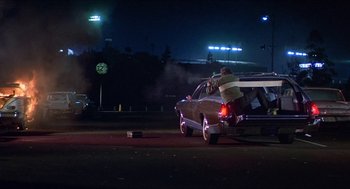 Movie still from “Hickey & Boggs” (1972), directed by Robert Culp – A man is standing in the back of a car; Wide shot, Low angle