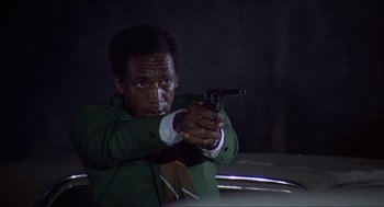 Movie still from “Hickey & Boggs” (1972), directed by Robert Culp – A man holding a gun in his hand; Medium shot, Low angle