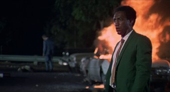 Movie still from “Hickey & Boggs” (1972), directed by Robert Culp – A man standing in front of a burning car; Medium shot, Low angle