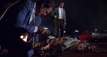Movie still from “Hickey & Boggs” (1972), directed by Robert Culp – A man is lying on the ground while another man holds a gun; Wide shot, Low angle