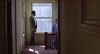 Movie still from “Hickey & Boggs” (1972), directed by Robert Culp – A man standing in front of a window in a room; Wide shot, Low angle