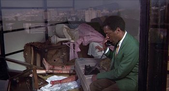 Movie still from “Hickey & Boggs” (1972), directed by Robert Culp – A man sitting on a chair talking on a phone; Medium shot, High angle