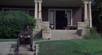Movie still from “Hickey & Boggs” (1972), directed by Robert Culp – A man in a suit sitting on the steps of a house; Wide shot, Low angle