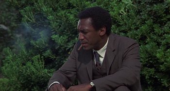 Movie still from “Hickey & Boggs” (1972), directed by Robert Culp – A man in a suit and tie smoking a cigarette; Medium shot, Low angle