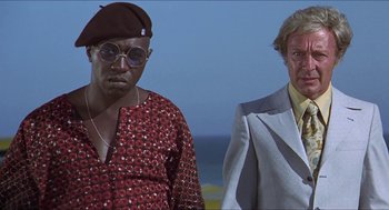 Movie still from “Hickey & Boggs” (1972), directed by Robert Culp – Two men standing next to each other near the ocean; Medium shot, Low angle