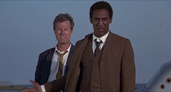 Movie still from “Hickey & Boggs” (1972), directed by Robert Culp – Two men standing next to each other wearing suits; Medium shot, Low angle